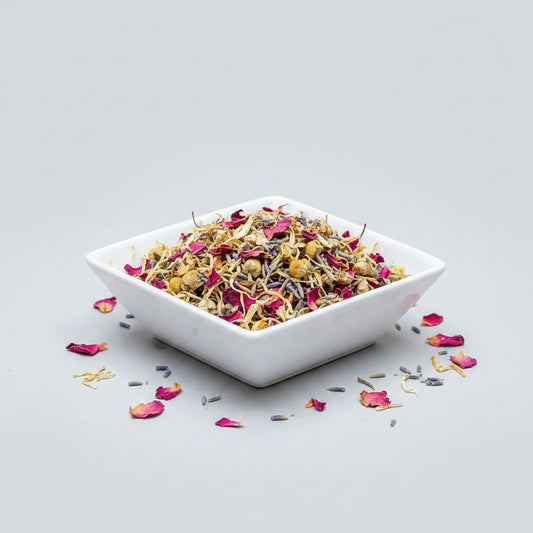 Assorted dried herbs and flowers on a white square plate with a white background