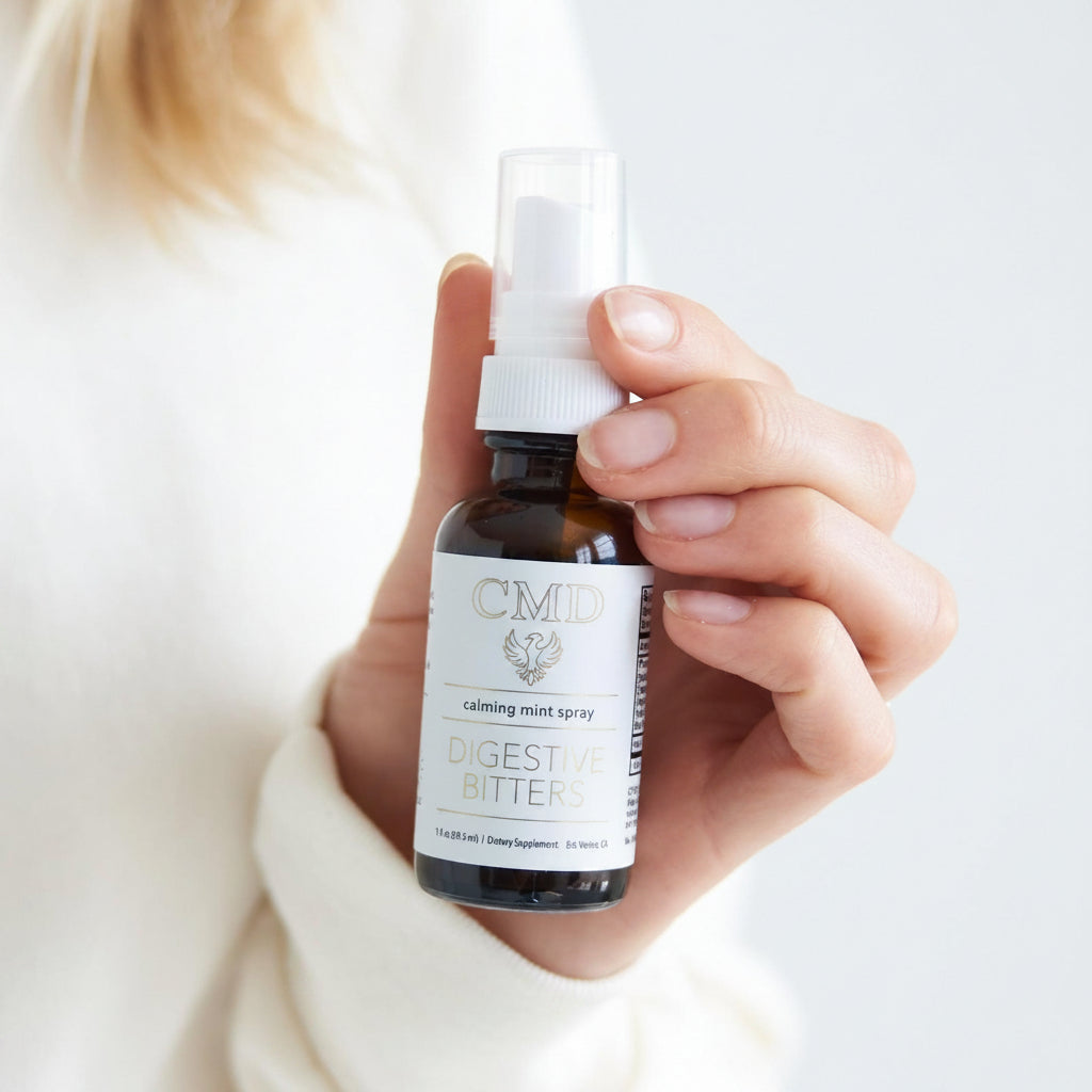 Hand holding a bottle of digestive bitter spray with a white label.