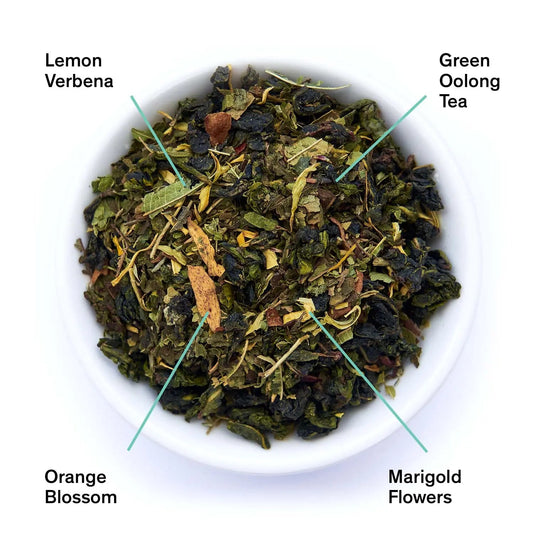 Tea leaves in a bowl with labels for Lemon Verbena, Green Oolong Tea, Orange Blossom, and Marigold Flowers.