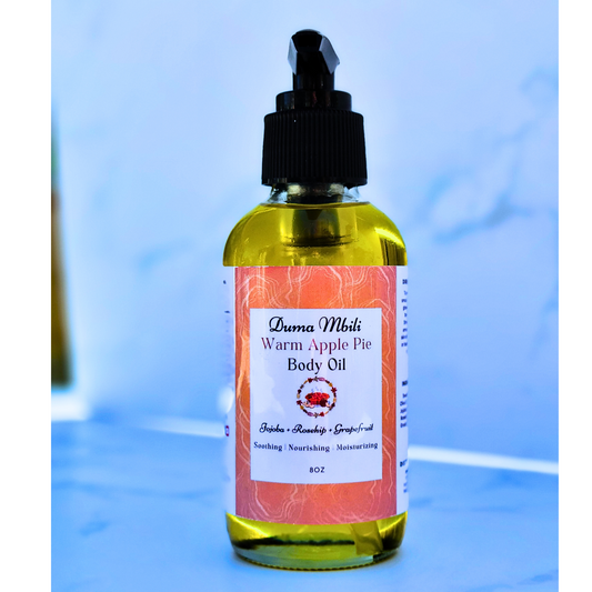 Bottle of Duma Muth Warm Apple Pie Body Oil on a blue background