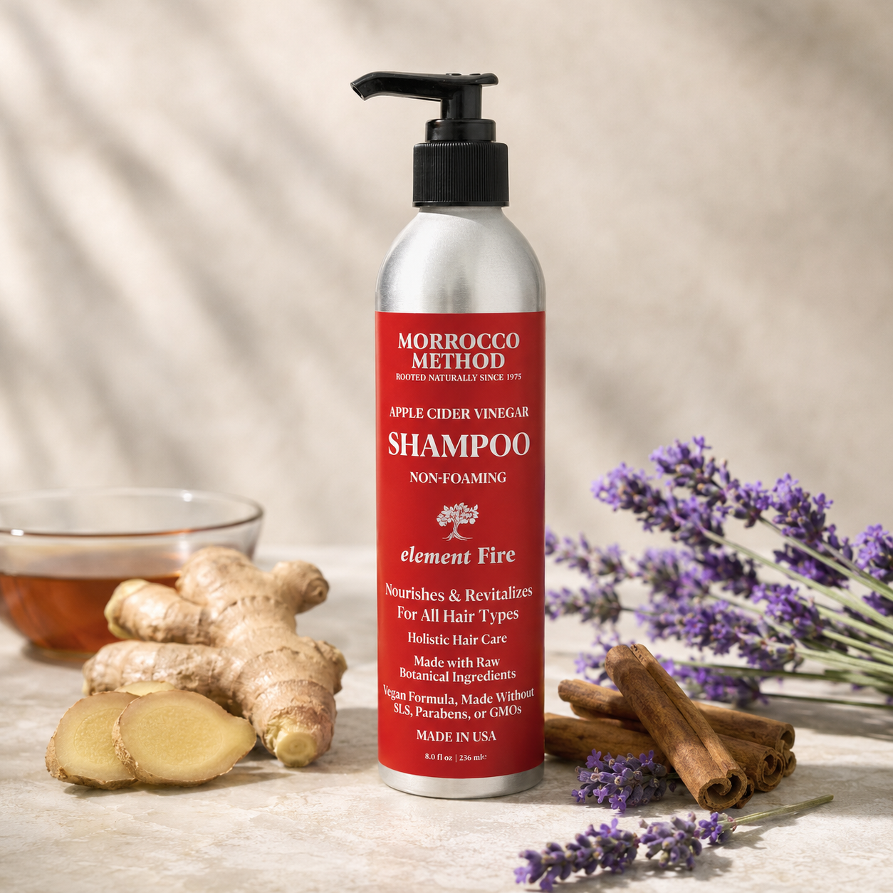 Morrocco Method shampoo bottle with ingredients like ginger, cinnamon, and lavender on a wooden surface.