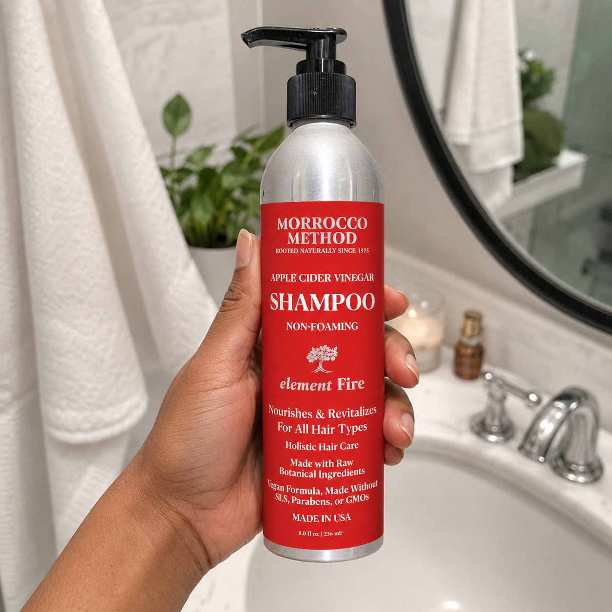 Hand holding a Morrocco Method shampoo bottle in a bathroom setting