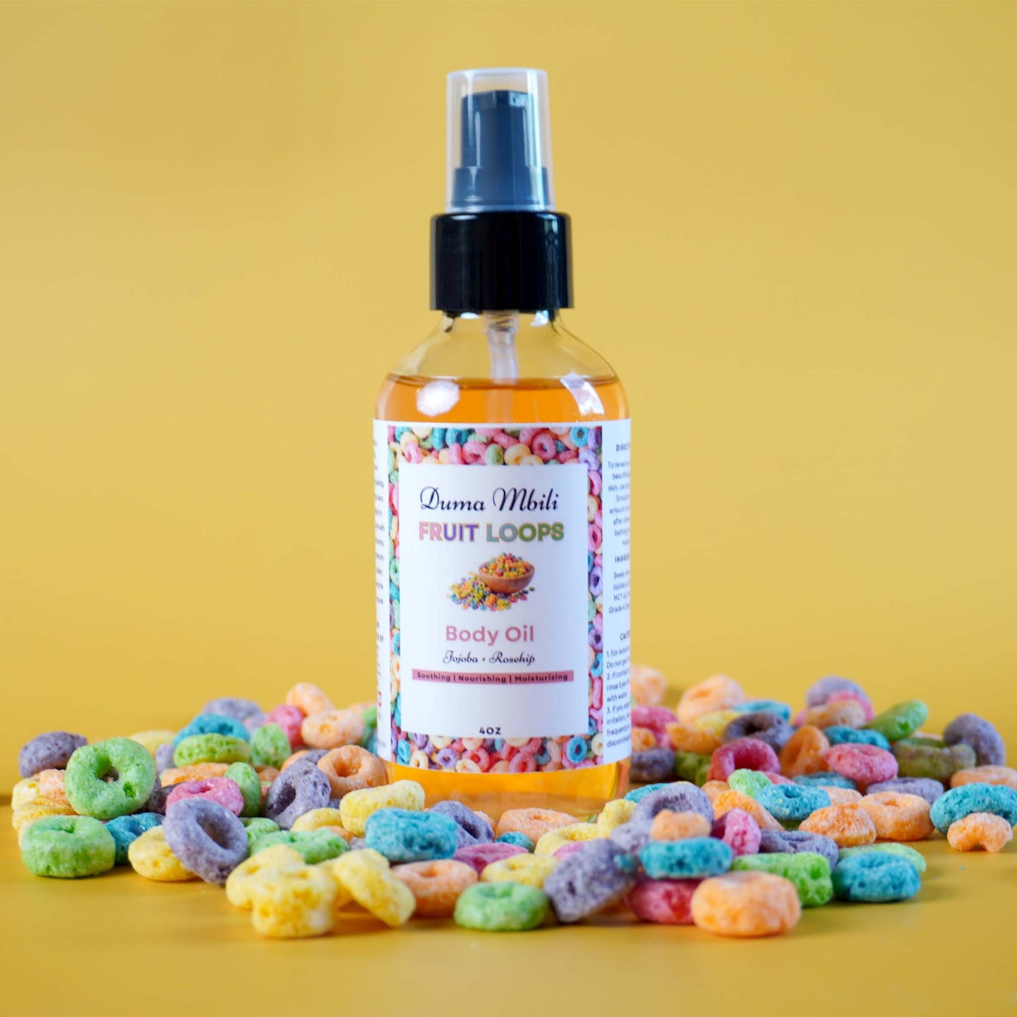 Bottle of 'Fruit Loops' body oil with colorful cereal loops on a yellow background
