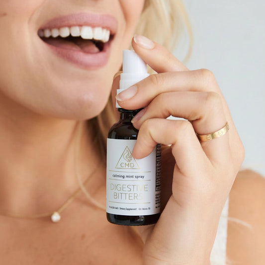 Person holding a bottle of 'Digestive Bitters' spray with a blurred background