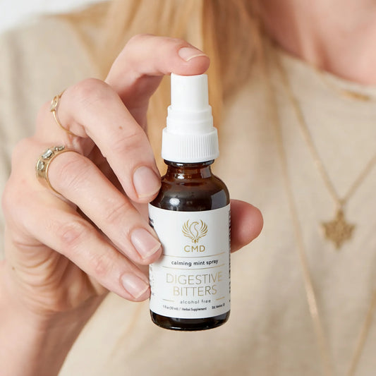 Hand holding a bottle of digestive bitters spray with a blurred background