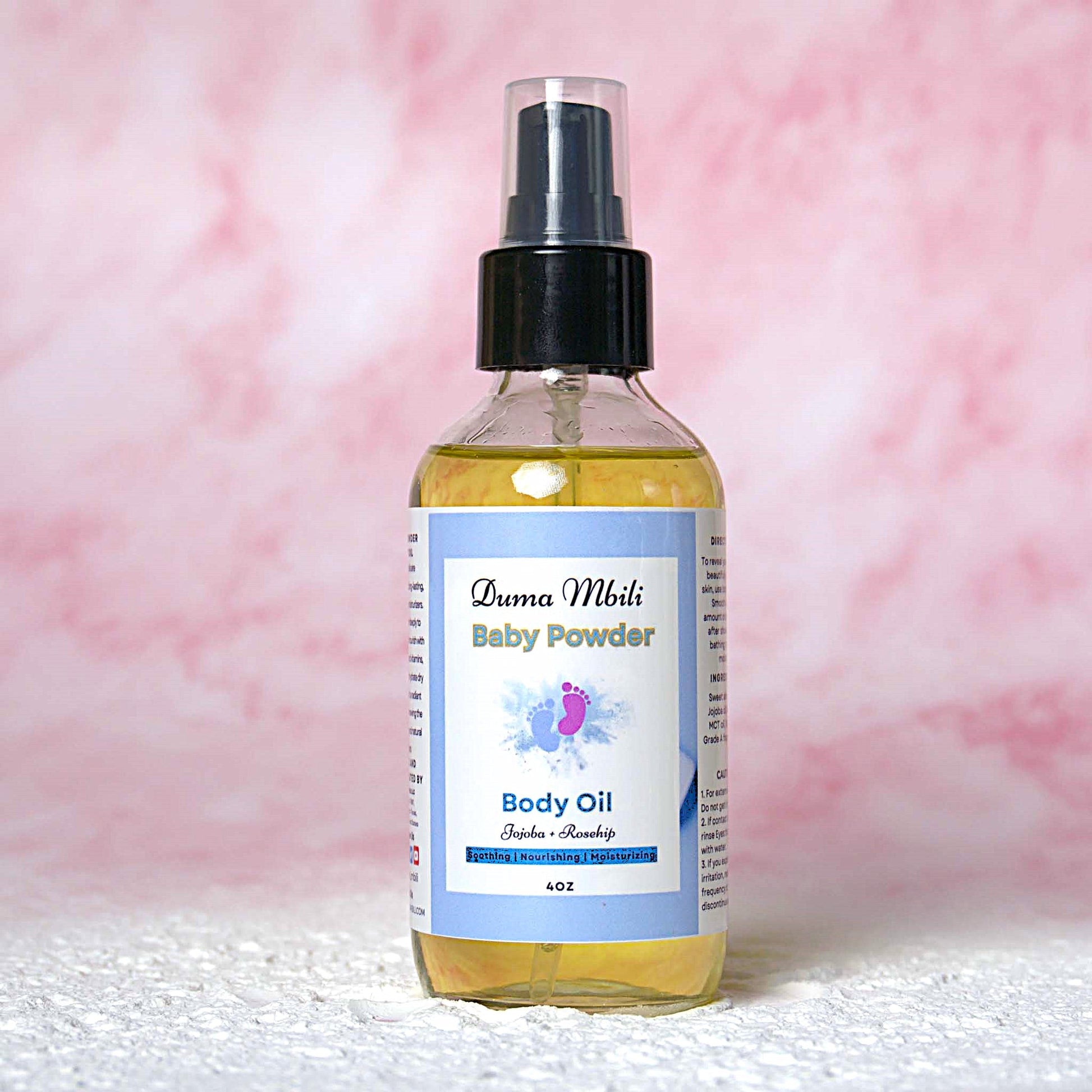 Bottle of Duma Mbuli Baby Powder Body Oil on a pink and white textured background
