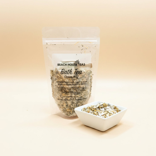 A clear stand-up pouch labeled Beach House Teas Bath Tea Creamy Mint, shown with a small white square dish of loose tea on a warm beige studio background.