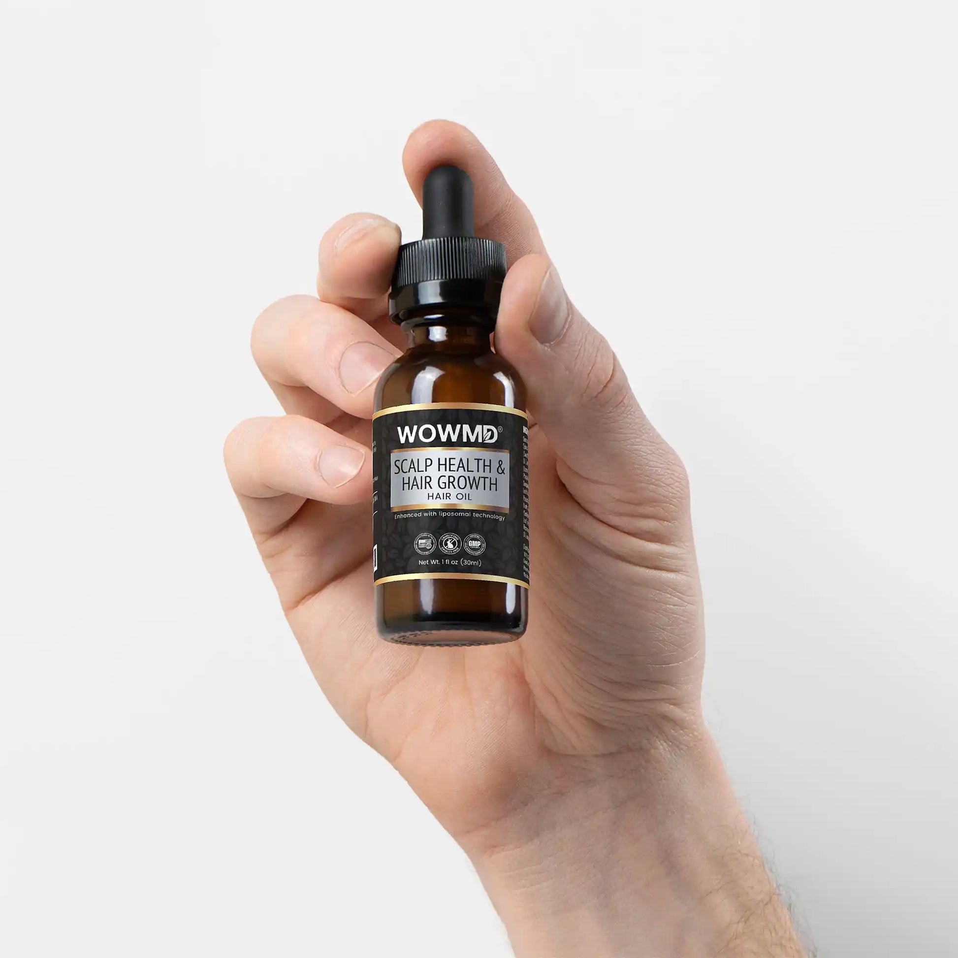 Hand holding a bottle of WOWMD scalp health and hair growth product against a white background