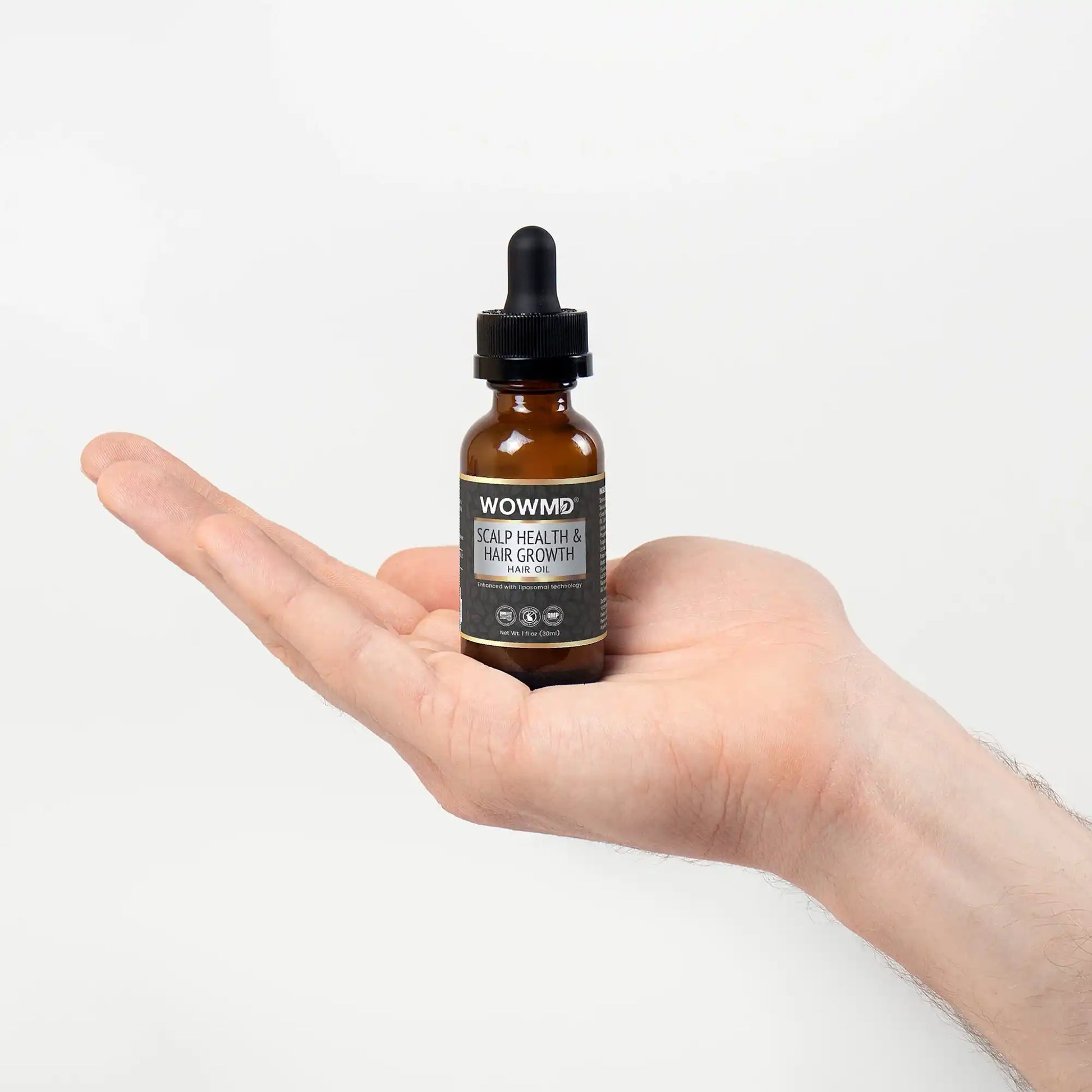 Hand holding a bottle labeled 'WOWMD Scalp Health & Hair Growth' against a white background